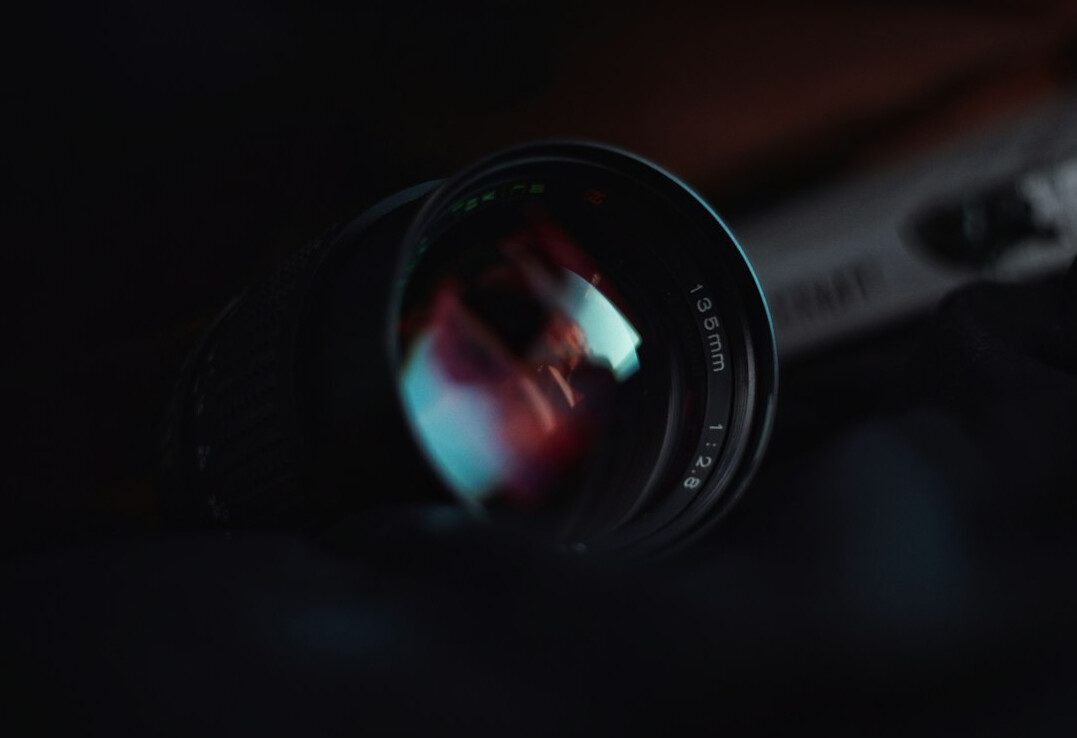 Dramatic close-up of a cinema camera lens with reflected light